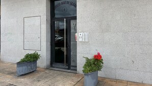 A building entrance with a glass door, a sign above the door, and two planters with plants. - Desconectaengalicia Mar de Silgar 2, 600 m from Silgar Beach (Pontevedra)