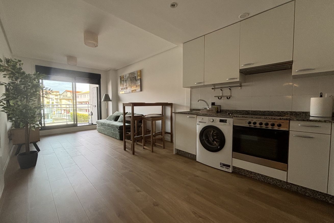 A modern kitchen with a washing machine, oven, and dining area with a view.
