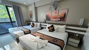 A hotel room with three beds, a large window with a view, a fan, and artwork on the wall. - Hanoi Homestay Minh Nhat (Hanoi)