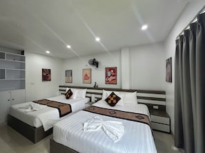 A hotel room with two beds, a ceiling fan, a coffee-themed wall decoration, and a window with curtains.