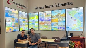 A reception desk with two individuals seated, surrounded by informational posters and a travel map. - Hanoi Homestay Minh Nhat (Hanoi)