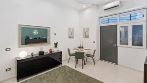 Una sala de estar moderna con un mueble de entretenimiento negro, una mesa de comedor redonda con sillas, un espejo grande y obras de arte en las paredes.