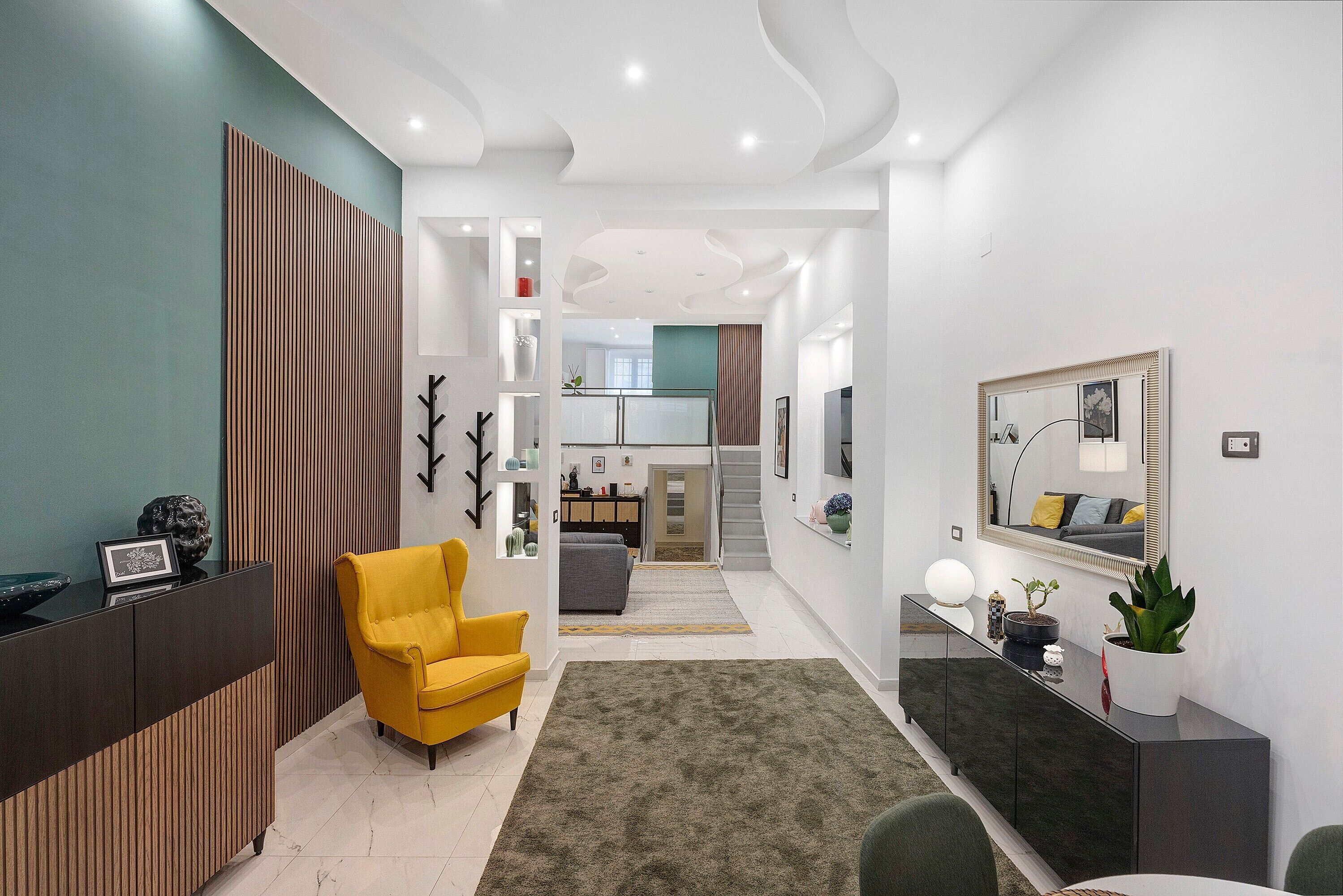 Un salon moderne avec un fauteuil jaune, un meuble en bois foncé et un grand miroir.