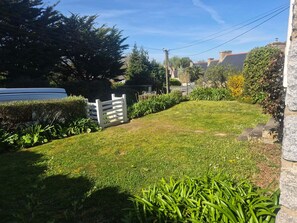 Een verzorgd gazon met een witte hek, omringd door verschillende planten en bomen.