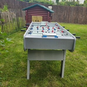 Uma mesa de futebol de bolso com estrutura metálica e superfície plana, sobre um gramado.