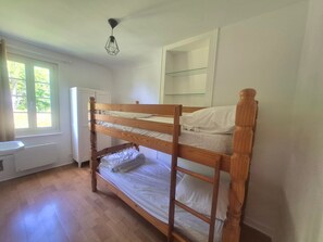 Un letto a castello con struttura in legno, materasso bianco e una singola lampada a sospensione.