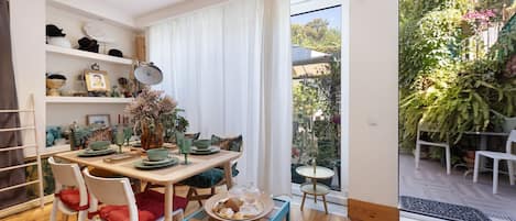 A dining area with a wooden table, chairs, and a view of a garden through a glass door.