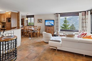 Ein modernes Wohnzimmer mit Sofa, Esstisch und Fernseher.