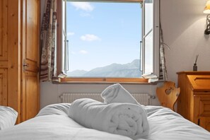 Ein Schlafzimmer mit großem Fenster, Holzmöbeln und Bergblick.