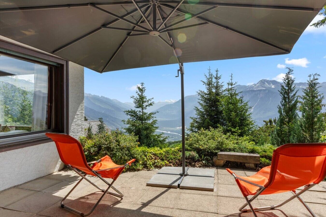 Un espace extérieur aménagé avec des sièges, offrant une vue sur les montagnes et doté d’un parasol de patio.