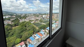 A window view of a cityscape with buildings, greenery, and a clear sky. - Premium studio apartment on the Golden Mile (ibague)