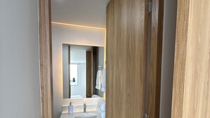A modern bathroom with wooden cabinetry, a white sink, and a mirror. - Premium studio apartment on the Golden Mile (ibague)