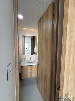Ein modernes Badezimmer mit Holzschränken, einem weißen Waschbecken und einem Spiegel.