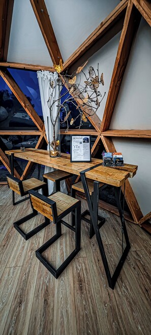 A dining area with a wooden table and chairs, a menu sign, and a decorative branch with butterflies.
