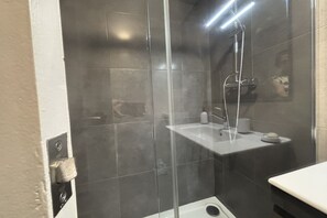 A modern bathroom with a glass-enclosed shower, a white sink, and a small mirror. - Desconectaengalicia Gaviota, 50 meters from Silgar Beach (Pontevedra)