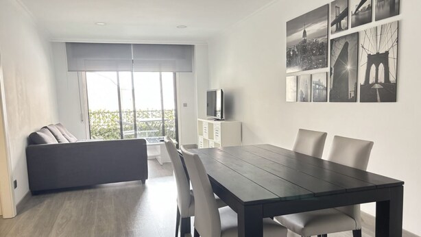 Uma sala de estar moderna com uma mesa de jantar, sofá e televisão sobre um móvel.