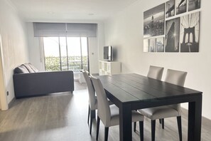Un salon moderne avec une table à manger, un canapé et un téléviseur posé sur un meuble.