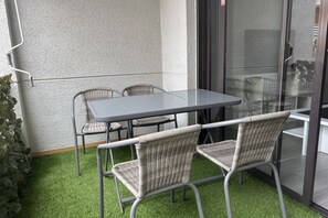 Un coin de pièce avec une cloison en verre, une table avec des chaises et un revêtement de sol en gazon synthétique.