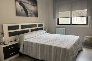 A bedroom with a bed, bedside table, lamp, and a window with blinds. - Desconectaengalicia Gaviota, 50 meters from Silgar Beach (Pontevedra)