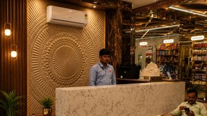 A hotel reception area with a marble counter, a chandelier, and a wall with a textured pattern.