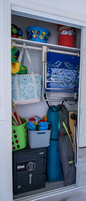 A storage area with a variety of items including a blue bucket, a red container, a blue suitcase, a green basket, and a black safe. - Welcome to The Coastal Crown, your ultimate luxury beach getaway! 👑<br>✨ Top-Floor Penthouse<br>🏖️ Steps to the Beach<br>🌊 Balcony Ocean Views<br>🛁 Master Suite Jacuzzi<br>📺 85" TV & Skylights (North Myrtle Beach)