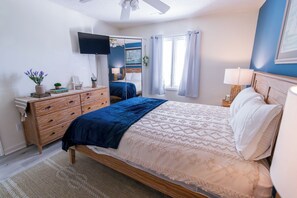 A bedroom with a bed, dresser, bedside table, lamp, and a television on the wall. - Welcome to The Coastal Crown, your ultimate luxury beach getaway! 👑<br>✨ Top-Floor Penthouse<br>🏖️ Steps to the Beach<br>🌊 Balcony Ocean Views<br>🛁 Master Suite Jacuzzi<br>📺 85" TV & Skylights (North Myrtle Beach)