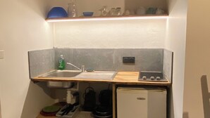 Une cuisine de taille réduite, équipée d’un évier, d’une cuisinière et de placards de rangement.