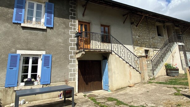 Un bâtiment à deux étages doté d’un balcon, d’un escalier et d’un petit espace extérieur aménagé pour s’asseoir.
