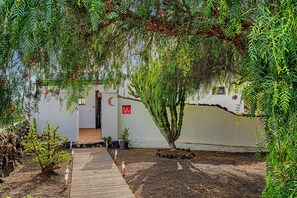 A pathway leading to a building with a 'V' sign, surrounded by greenery and a stone wall. - La Casita II in Masdache: Tranquility in the Heart of Lanzarote (Masdache)