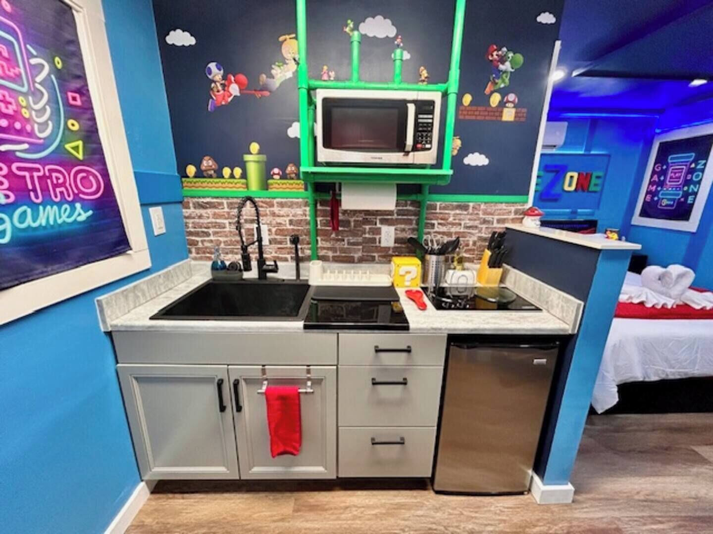 A kitchen with a microwave, sink, and cabinets, decorated with retro gaming characters.