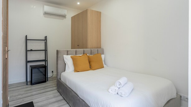 Une chambre à coucher comprenant un lit, une armoire, une étagère et un appareil de climatisation.