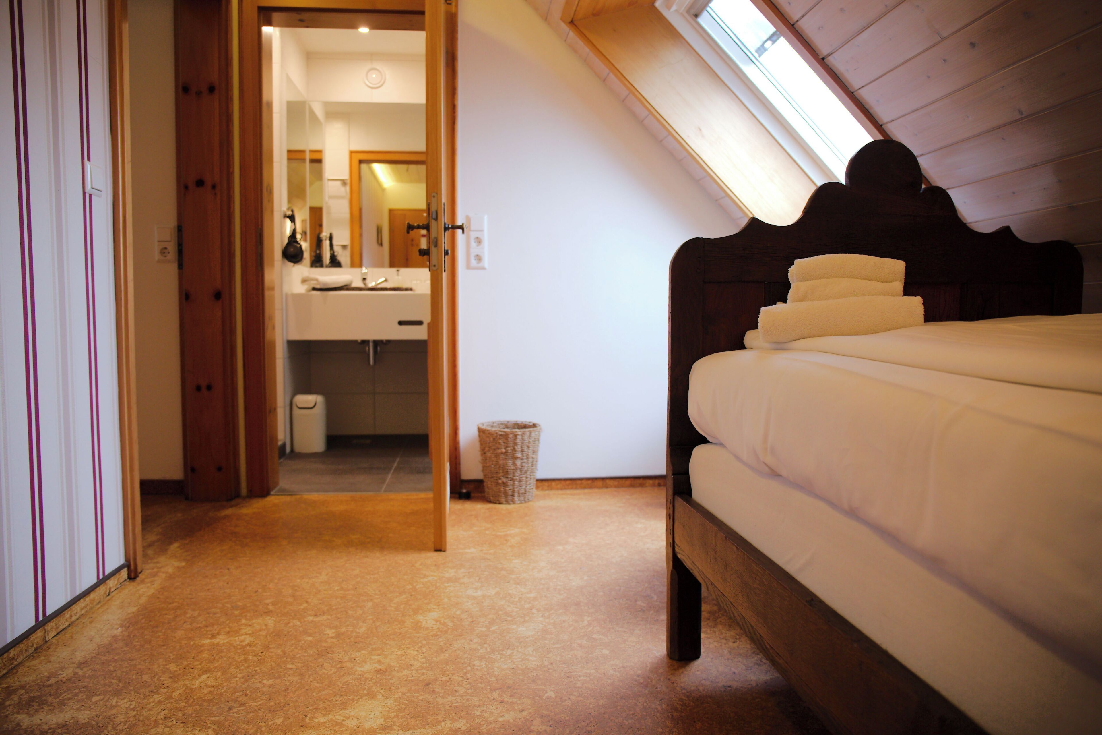 A bedroom with a wooden bed, a bathroom with a mirror, and a skylight.
