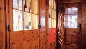 A wooden interior with a glass display case containing bottles, a curved wooden door, and a window with frosted glass.