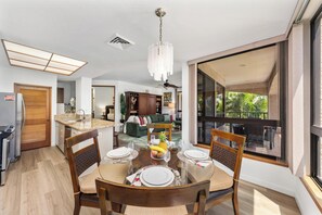 Ein Essbereich mit einem runden Tisch, gedeckt für vier Personen, einer Chandelüster und Blick ins Freie.