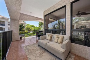 Ein Balkon mit einer Couch, einem Esstisch und Stühlen.