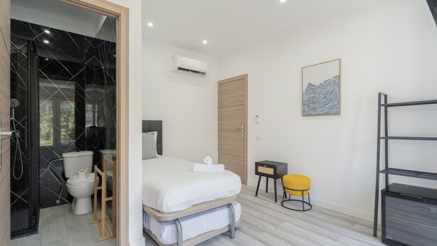 Ein modernes Schlafzimmer mit Bett, Nachttisch und einem kleinen Hocker.