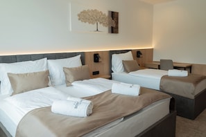 Une chambre d’hôtel avec deux lits, un bureau et une œuvre d’art accrochée au mur.