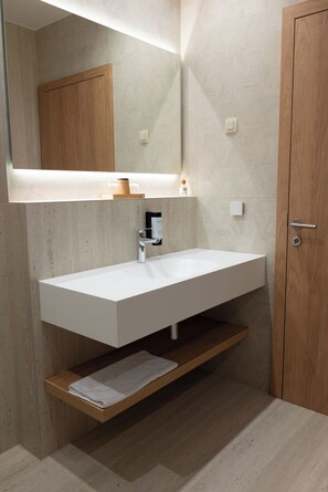 A modern bathroom with a white sink, wooden vanity, and a mirror above the sink.