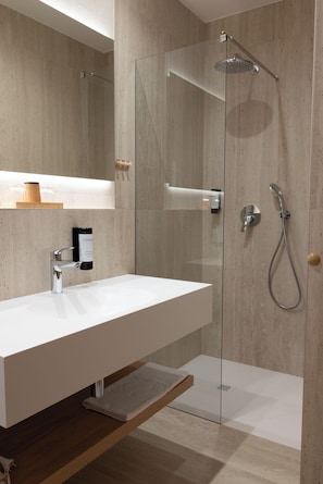 Une salle de bain moderne avec une douche à parois de verre, un lavabo blanc et une étagère en bois.