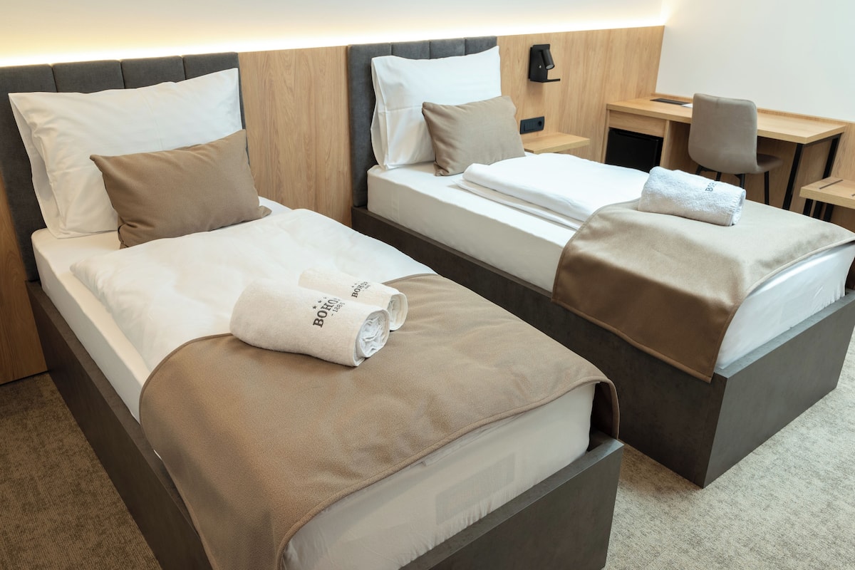 A hotel room with two beds, a desk, and a chair.