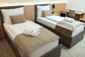 Une chambre d’hôtel avec deux lits, un bureau et une chaise.