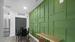 A modern kitchen with a built-in refrigerator, a dining area with a wooden table and chairs, and a green accent wall. - Hyde Park 1/1 private residence 8 (Tampa)