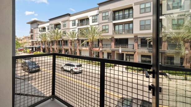 A multi-story residential building with balconies, a parking lot, and palm trees. - Hyde Park 1/1 private residence 8 (Tampa)