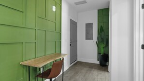 A room with a green wall, a wooden table, a brown chair, a grey door, and a potted plant. - Hyde Park 1/1 private residence 8 (Tampa)