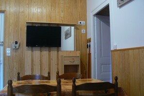 Ein Essbereich mit einer Holzwand, einem Tisch und einem darüber montierten Fernseher sowie einer Tür zu einem anderen Raum.