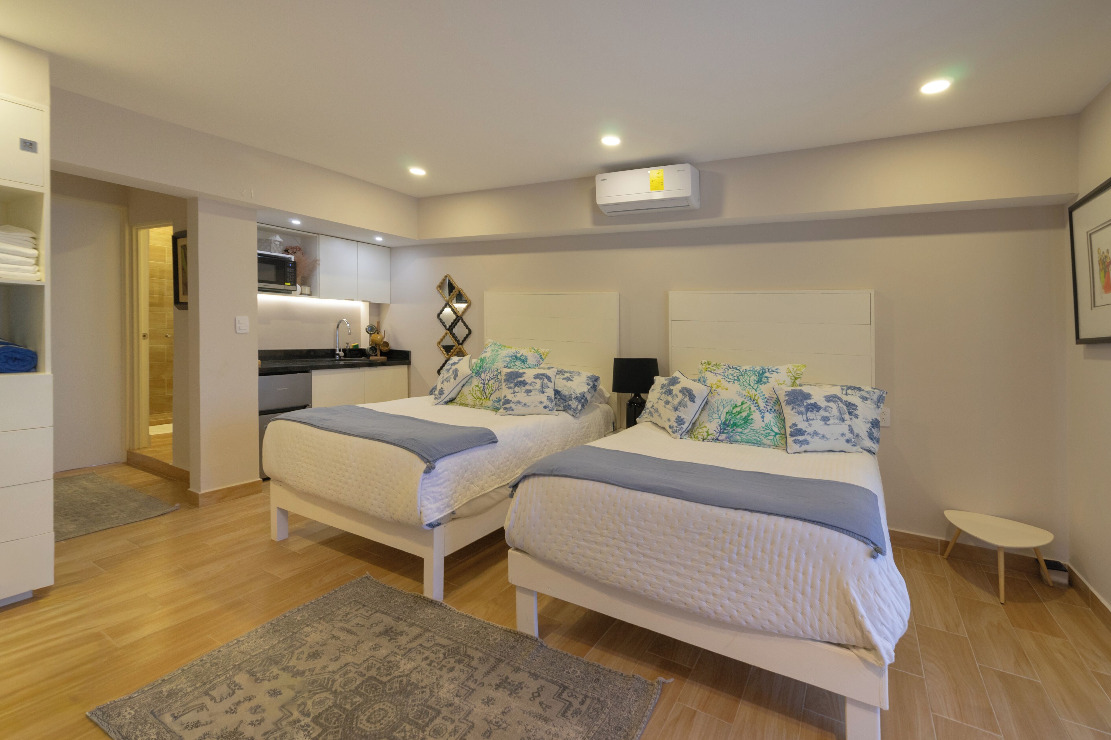 Ein Schlafzimmer mit zwei Betten, einer kleinen Küchenzeile und einem Badezimmer.