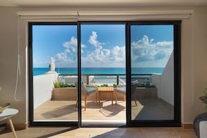 Ein Balkon mit Meerblick, einer Statue und einem Tisch mit Stühlen.