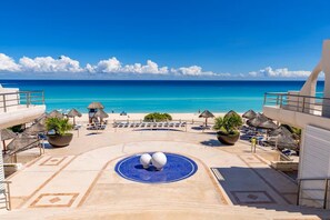 Ein Poolbereich eines Resorts mit Liegestühlen, Sonnenschirmen und Blick auf den Ozean.