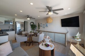 Ein stilvoller Wohnraum mit Küche, Essbereich und einem Balkon mit Fernseher.