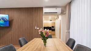 Un comedor con una mesa de madera, sillas grises y un jarrón con flores.